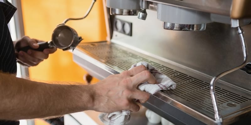 male hand wiping coffee machine with cloth