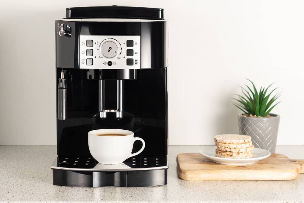 Modern espresso coffee machine with a cup in interior of kitchen closeup.