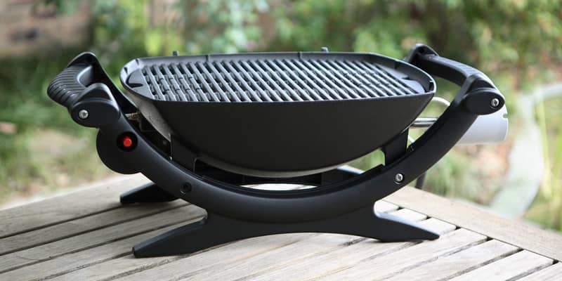 a Weber Baby Q barbecue grill in a garden setting