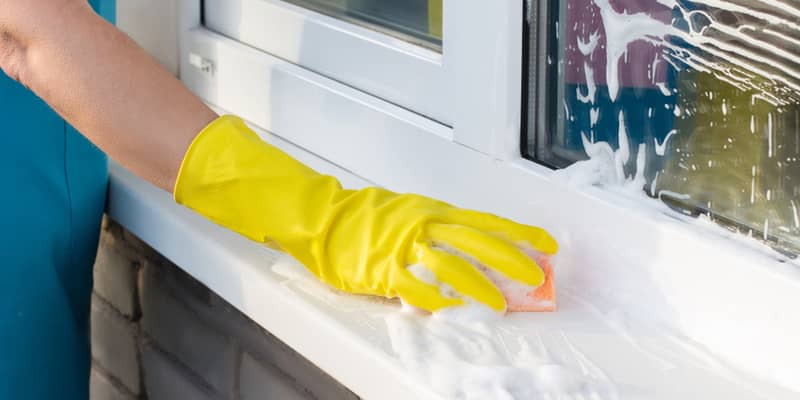 lady hand with yellow gloves cleans window sill