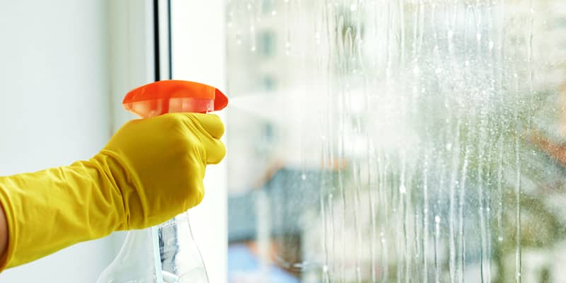 Woman cleaning window at home, closeup