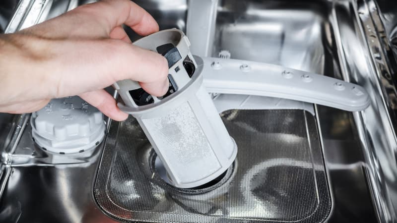 Man hands cleans the filter in the dishwasher.