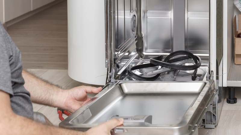 man disassembling the dishwasher for maintenance