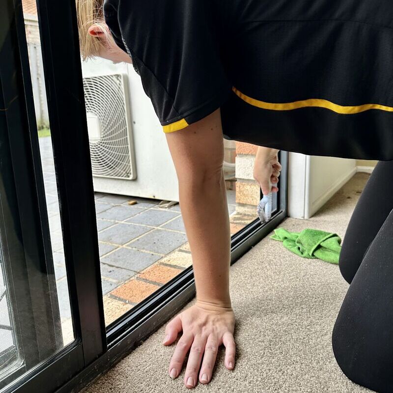Professional cleaner, Jarna, brushes a sliding door track