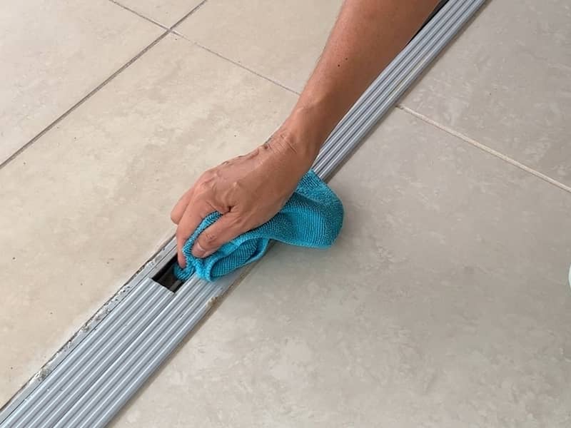 Professional cleaner wipes a sliding door track's grooves with microfibre cloth