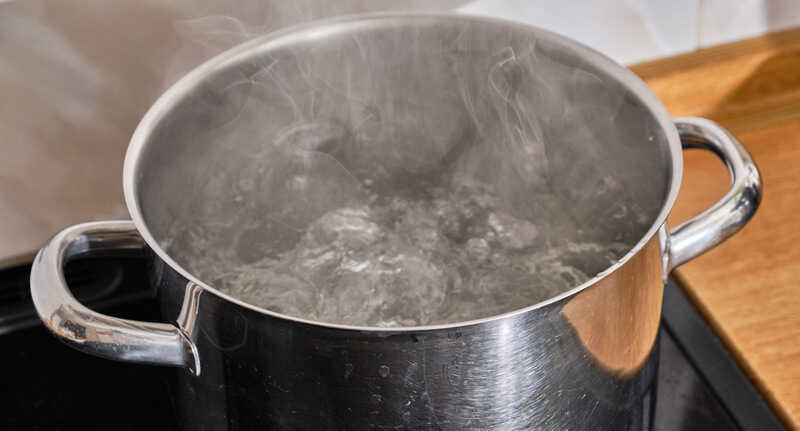 Boiling water in pan on electric stove in the kitchen