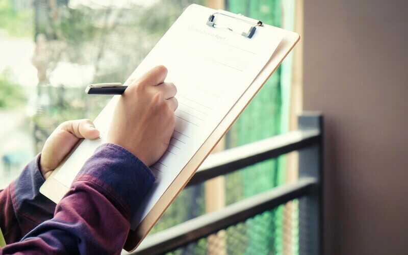 male hands writing on a checklist during a home inspection 