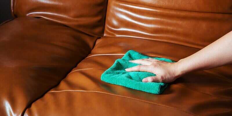 Woman hand wiping brown leather sofa