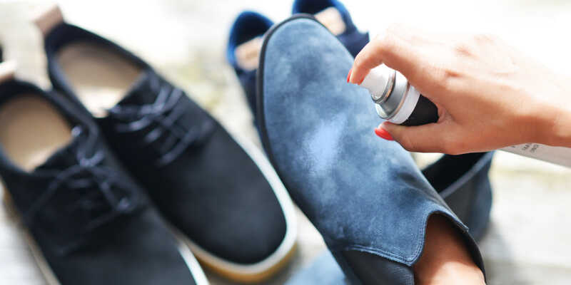 woman hands spraying suede leather shoe with suede protector