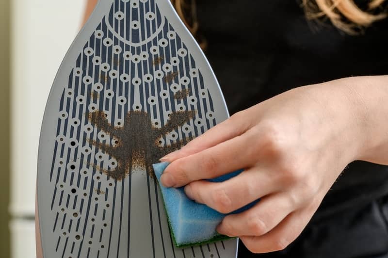 cleaning a burnt iron soleplate with sponge