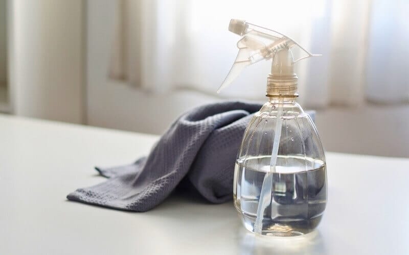 spray bottle with vinegar solution and a microfibre cloth on top of a table