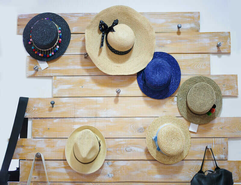 Classic, vintage women straw hats hanging on a wooden decorative desk on the white wall background