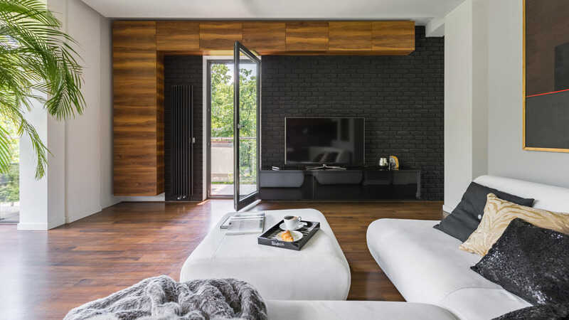 Elegant living room with black brick wall, wooden floor and shelves and balcony door