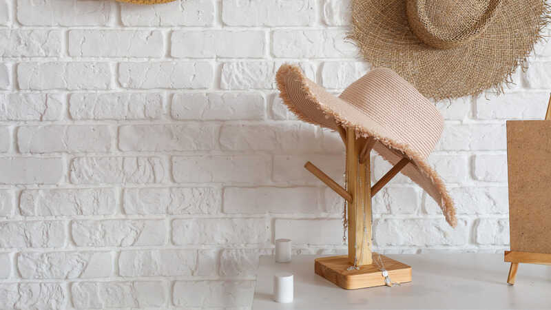 Stylish female hat with jewelry on shelf in room