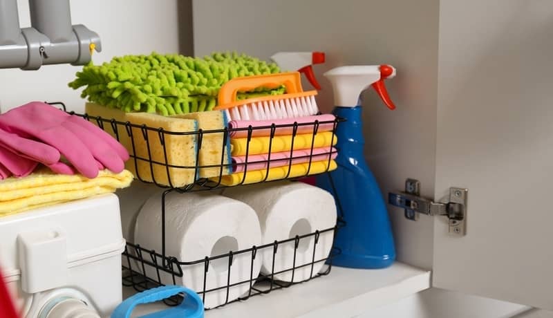 Open under sink cabinet with different cleaning supplies in kitchen