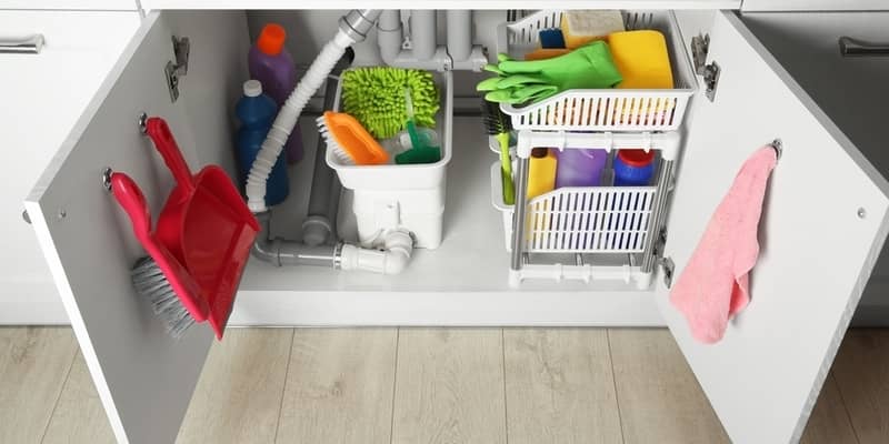 Different cleaning tools and supplies in open cabinet under sink