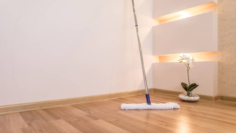 White mop cleaning wooden floor in house with flower and nice interior lighting on background