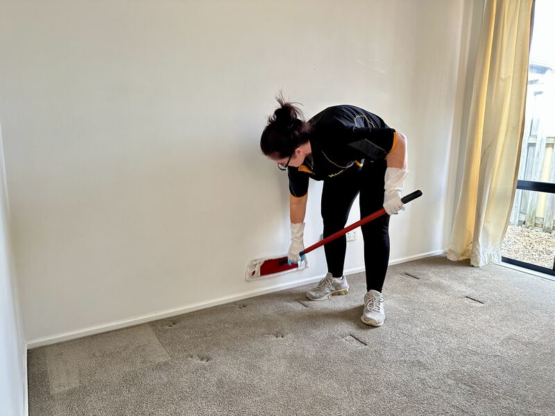 professional cleaner using mop to clean the walls and skirting boards