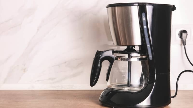 Empty drip coffee maker on kitchen wooden countertop against marble backdrop