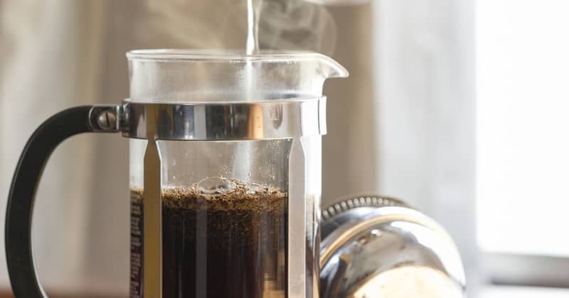 Coffee brewing in a French press in warm morning light;