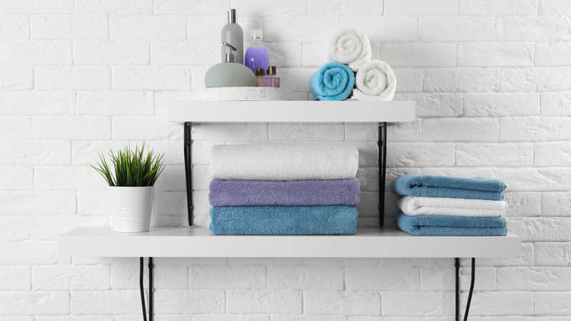 Shelves with clean towels and toiletries on brick wall