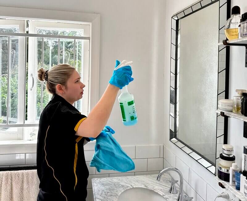 Kate-lyn spraying the bathroom mirror