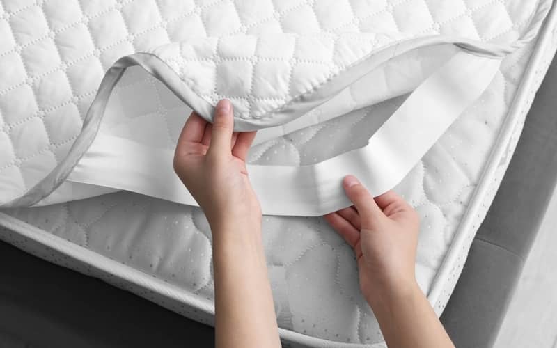 Woman putting protector on mattress