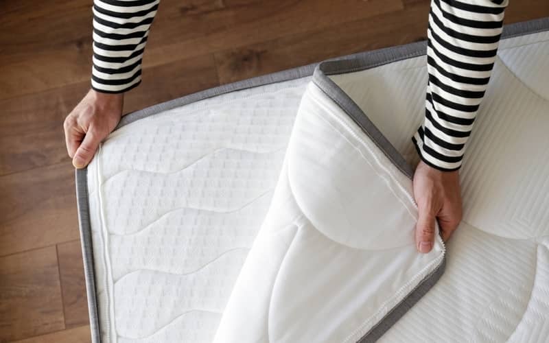 Hands unzipping hypoallergenic foam mattress protector