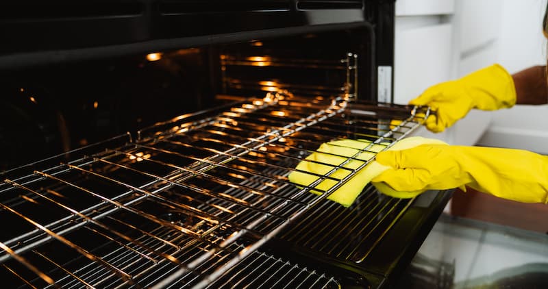 a cleaning professional wiping the racks of an oven