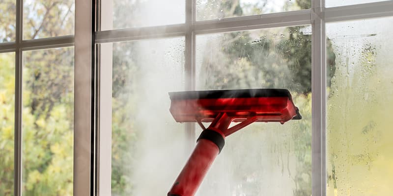 close up of cleaning window glass with steam mop