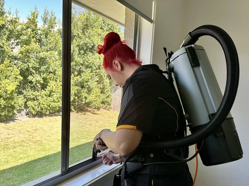 professional cleaner cleaning window tracks by using a vacuum