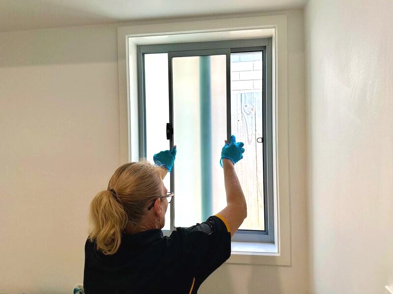 professional cleaner removing fly screen to clean windoe
