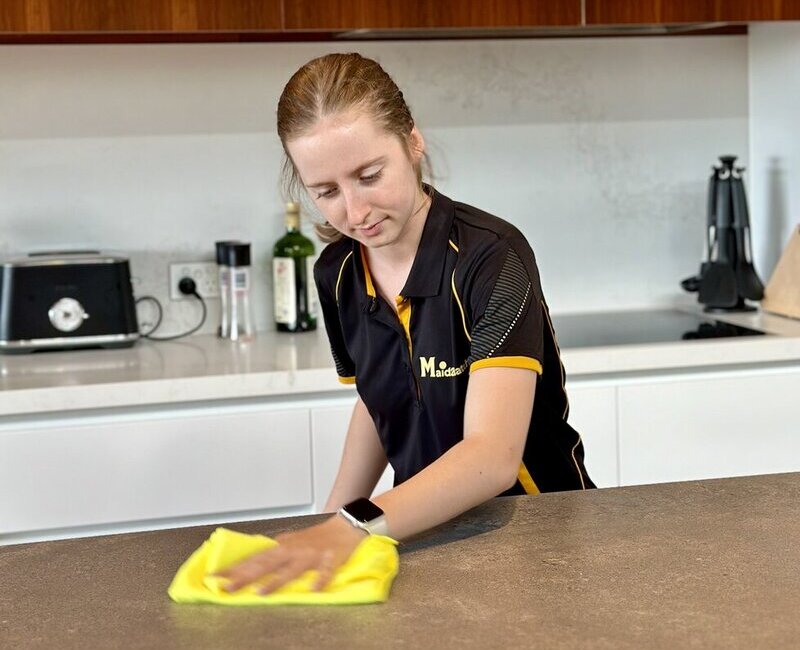 Professional cleaner, Jade wiping the stone benchtop with microfibre cloth