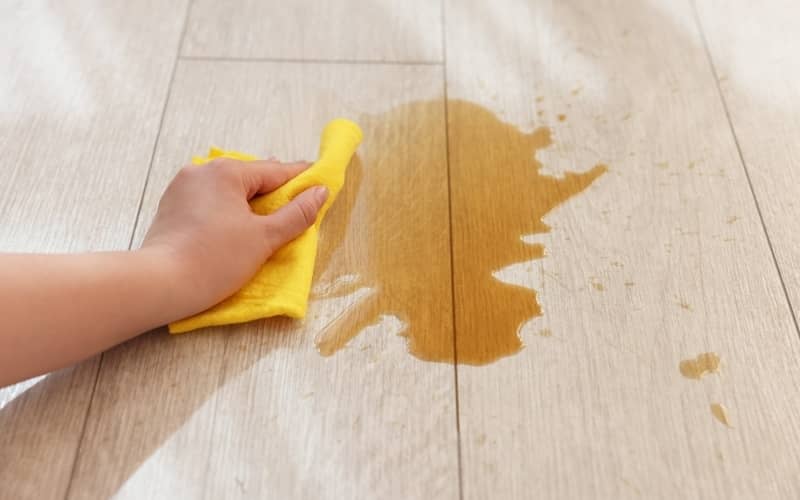 hand holding cloth cleaning spill on vinyl floor