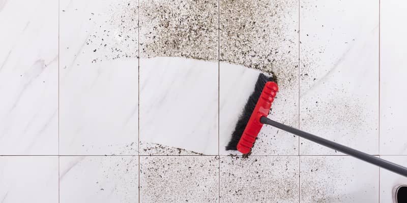 Broom cleaning dirt on tiled floor at home