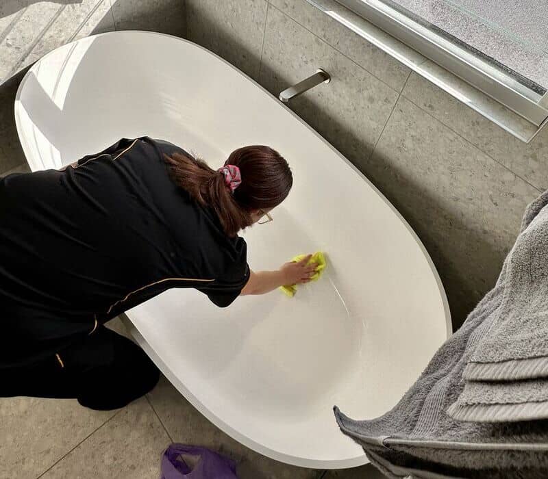 Maid2Match professional cleaner Kisten cleaning the bathtub with yellow microfibre cloth