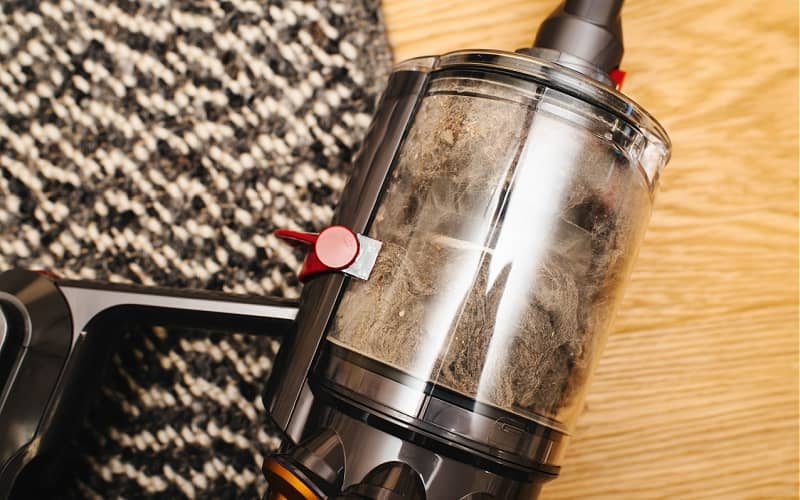 dust bin of a vacuum cleaner filled with dust and other particles