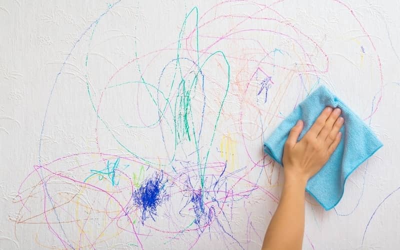 hand wiping the permanent marker off the wall with a cloth