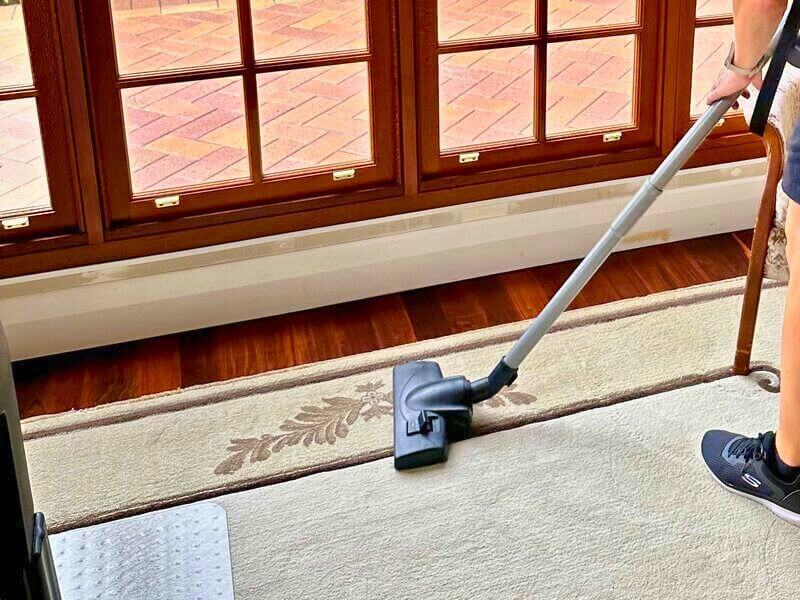 house cleaner using vacuum on carpet