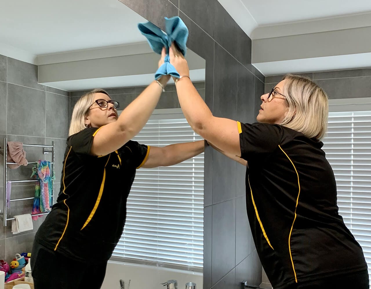 Michelle cleaning bathroom mirror Maid2Match professional cleaner Michelle cleaning bathroom mirror