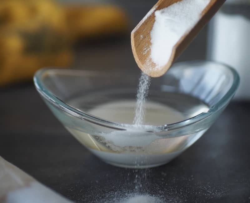 pouring baking powder into a bowl with water