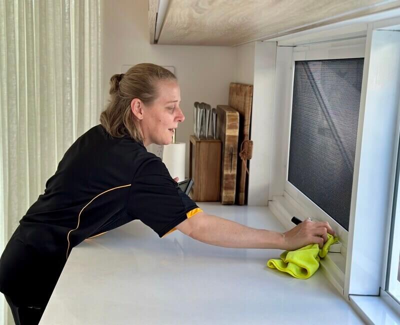 Brisbane-professional-cleaner-cleaning-window-fly-screen Professional cleaner Nicole cleaning the surrounding area of a window with fly screen