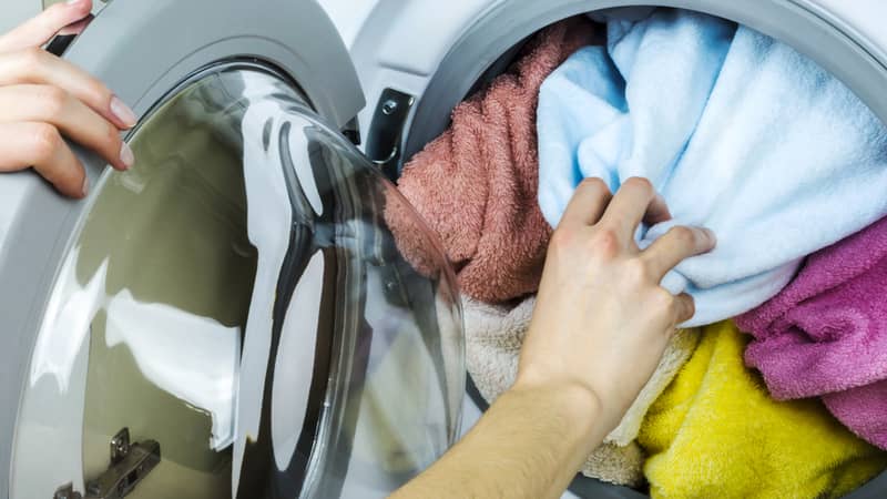 hand removing clothes or towels from the washing machine