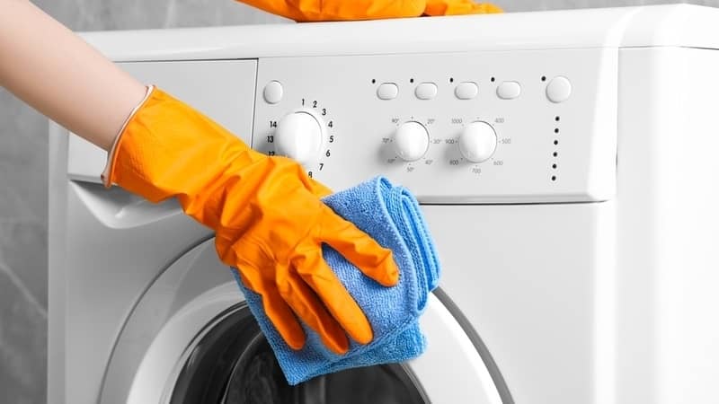 hand wiping the front load washing machine with a cloth