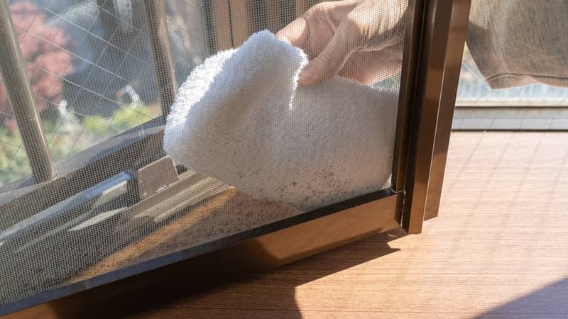 Cleaning the screen door with a cloth.