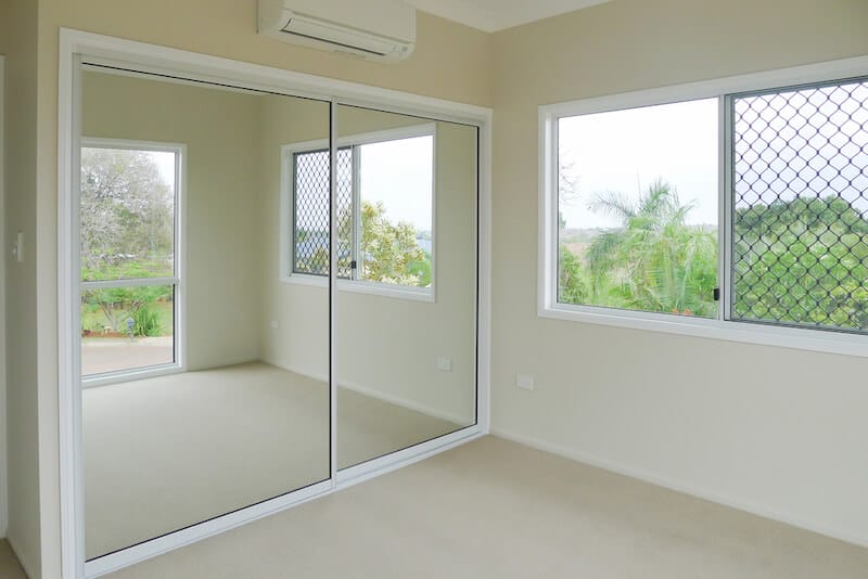 Room with large mirrors and open windows with security screen