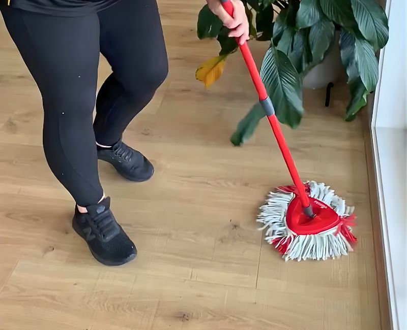 professional house cleaner using spin mop on floating floorboards