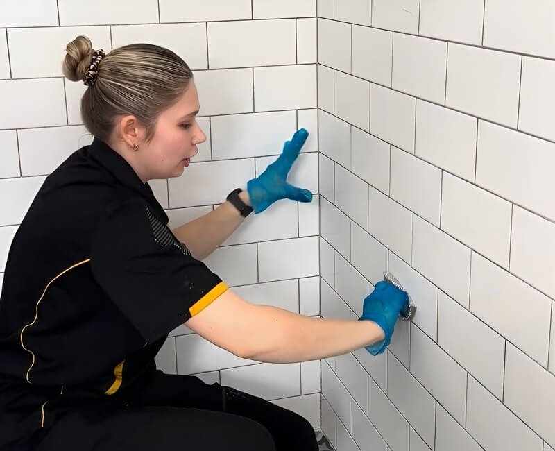 Maid2Match cleaner Kate-lyn cleaning the grout of the shower wall