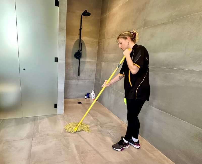 Brisbane house cleaner Casey mopping bathroom floor tiles