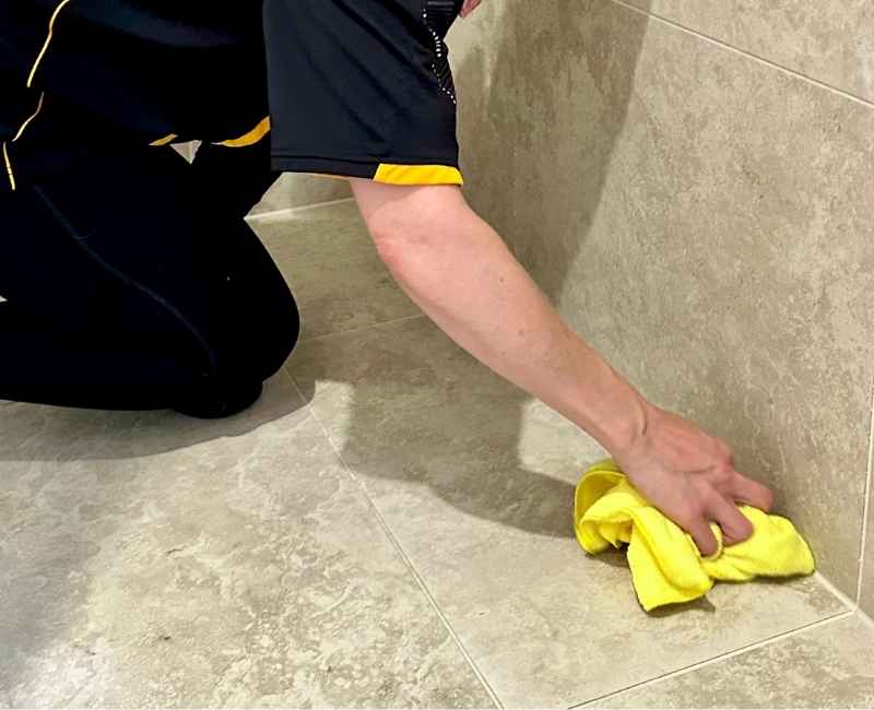 Maid2Match Brisbane professional house cleaner Nicole wiping stone travertine tiles with microfibre cloth